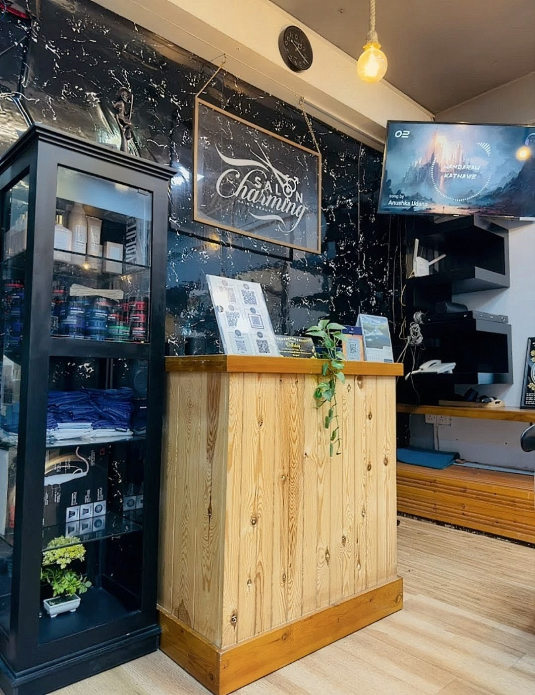 Reception counter with black marble wall and gold-framed Salon Charming sign